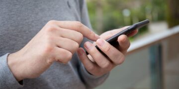 Man-hand-holding-iPhone-11_shutterstock_1683615031_DenPhotos